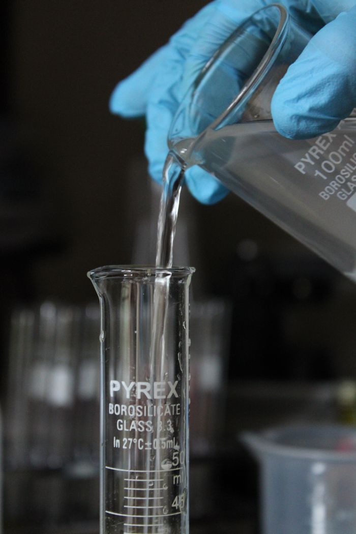 who-we-are Scientist pouring liquid in lab for experiment, emphasizing precision and scientific research.
